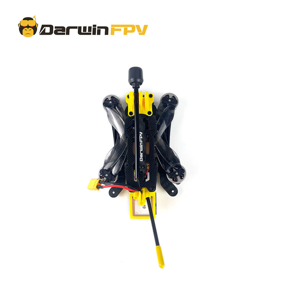 Top view of the folded DarwinFPV FoldApe 4 FPV drone, showing its compact design with folded propellers, carbon fiber frame, yellow XT60 connector, and long-range antenna